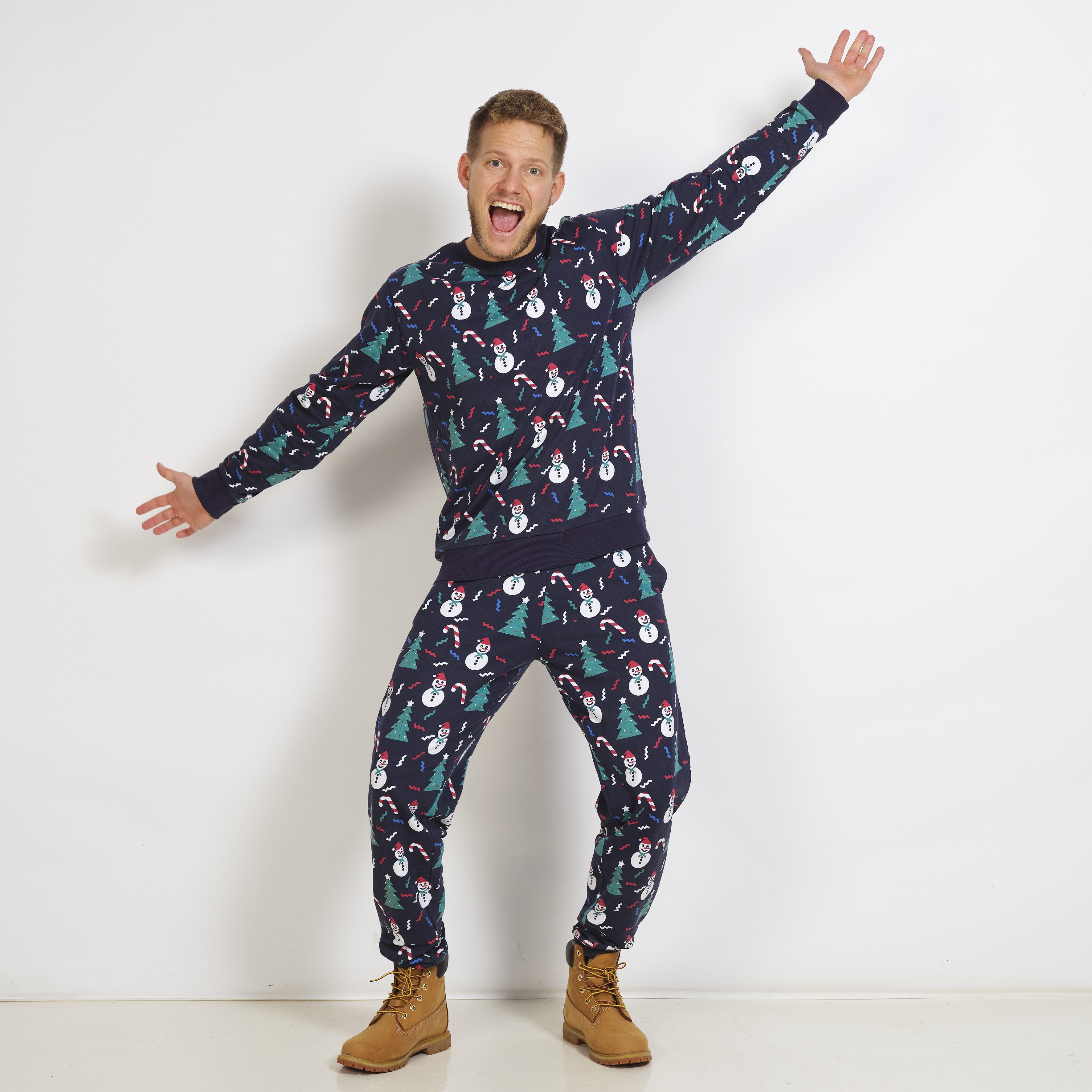 Eine Frau in einem dunkelblauen Weihnachtspulli mit Weihnachtsbäumen und Schneemännern.